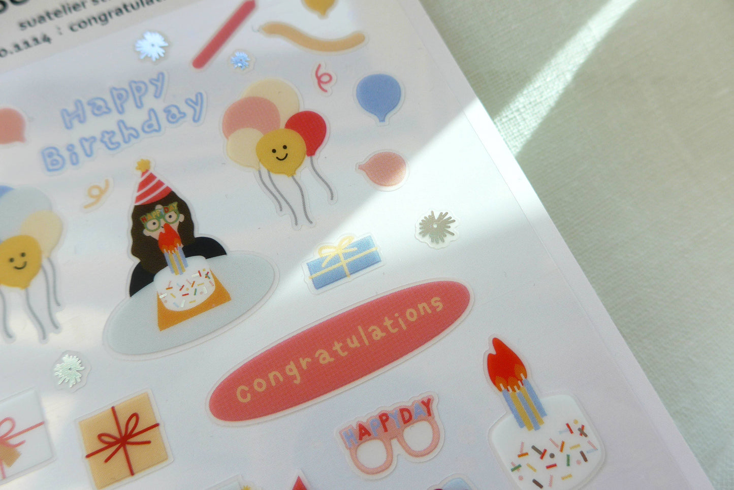 Sheet of birthday-themed Suatelier stickers with birthday party illustrations on a white background.