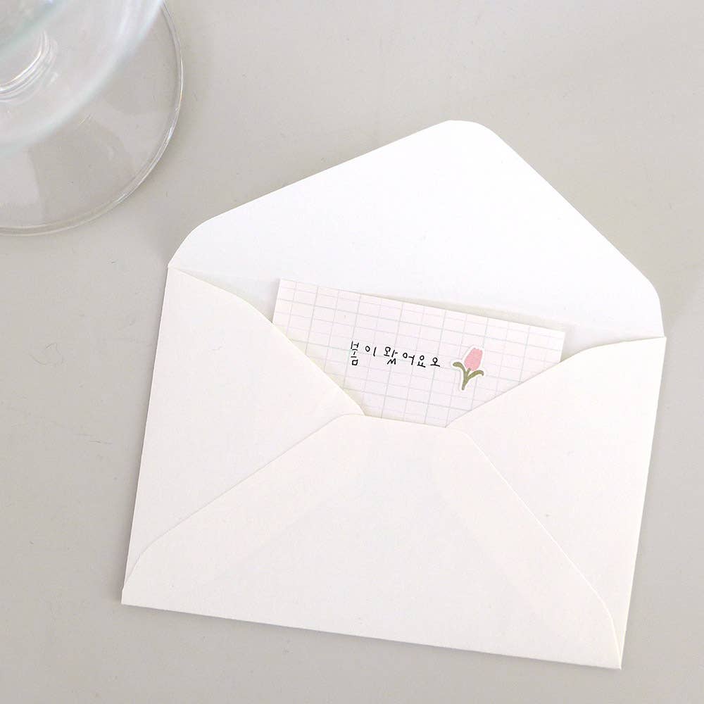 White envelope with a pink flower sticker on a gray surface