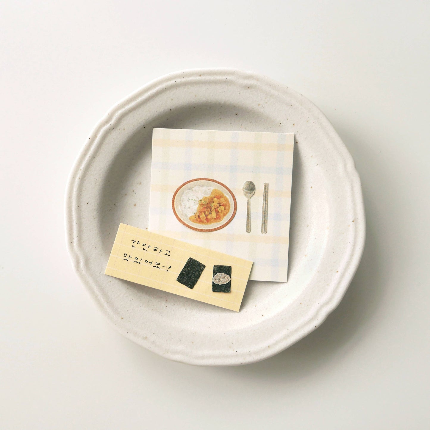 Two cards with decorated stickers on a textured ceramic plate with a white background