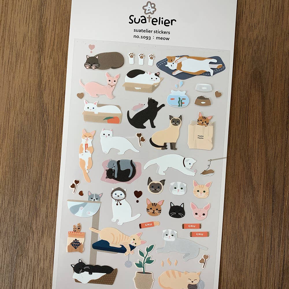 Sheet of Suatelier cat-themed stickers on a wooden surface