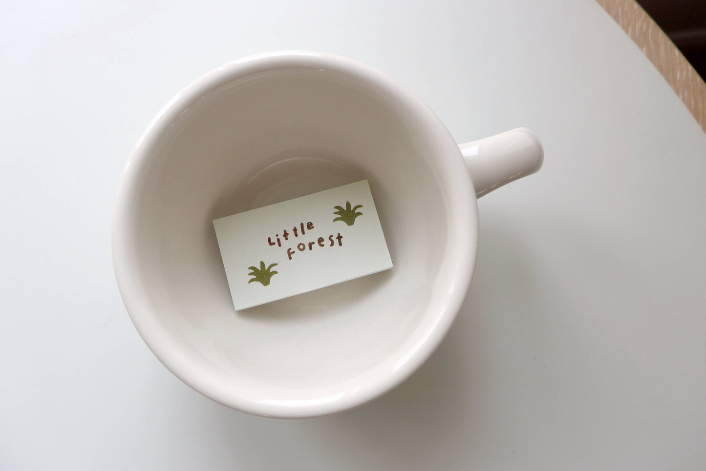 White mug with a small card inside on a light surface