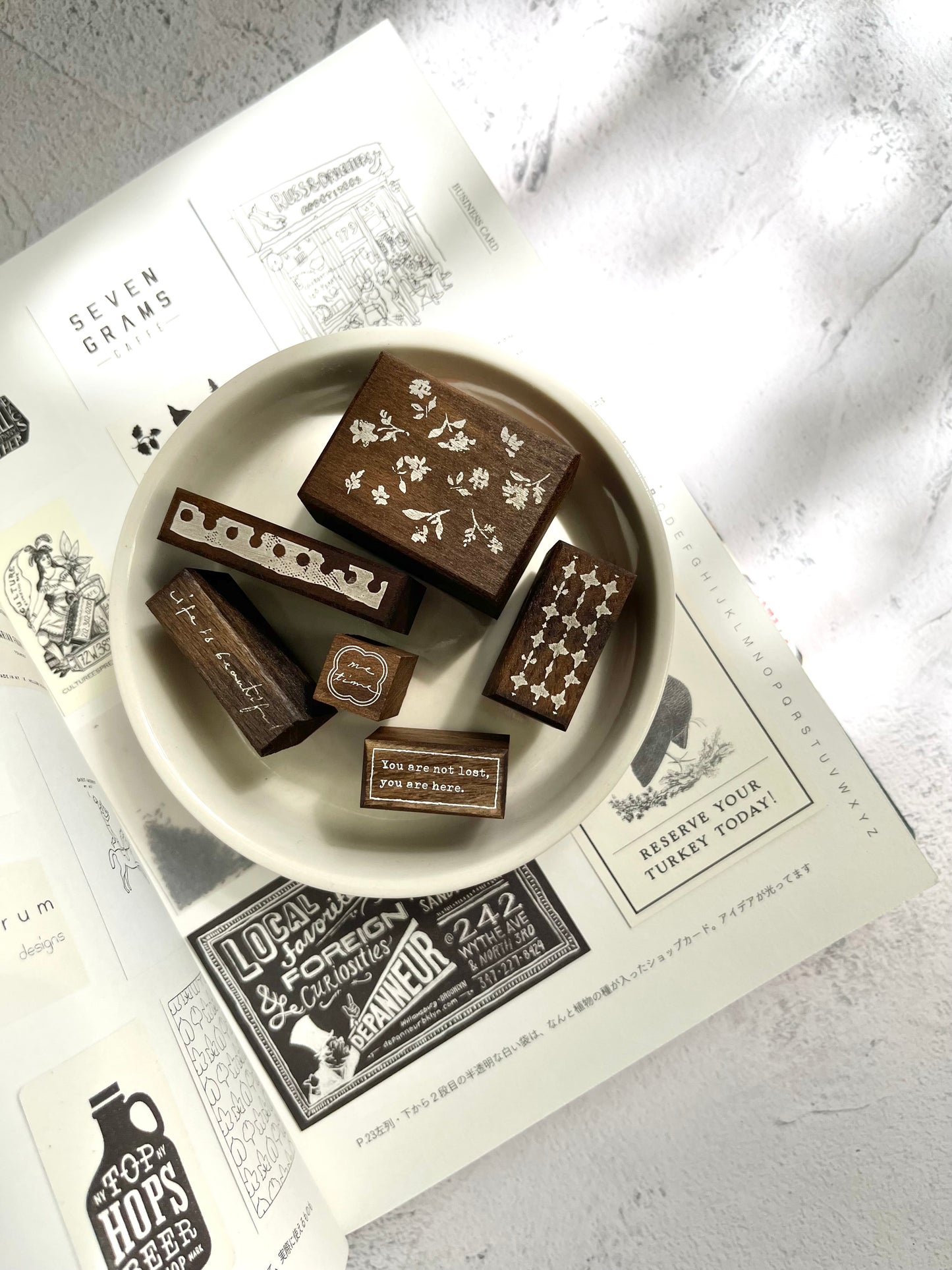 Dark brown wooden rubber Pion stamps in a ceramic white bowl on a book