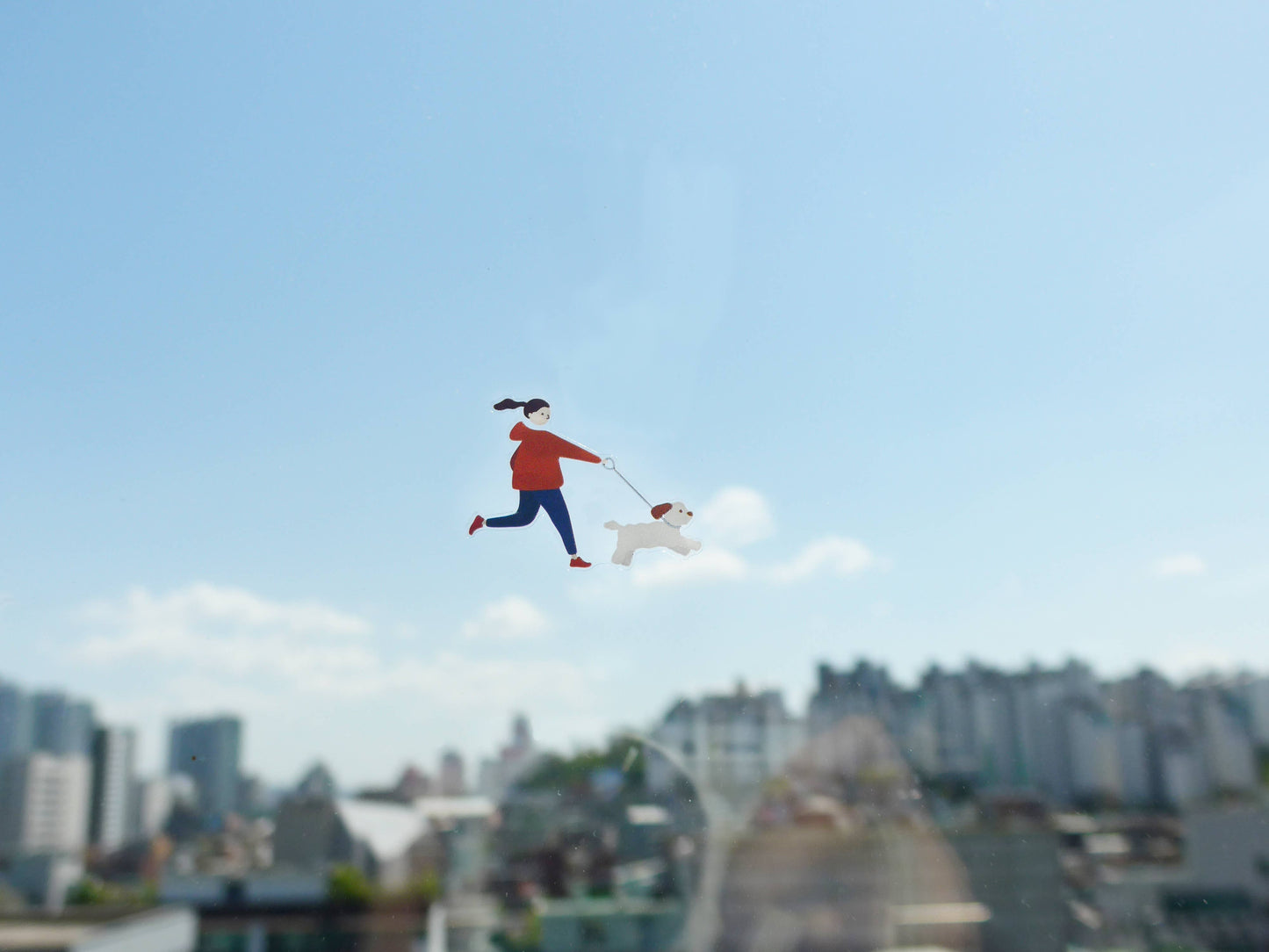 Sticker of person walking a dog with a cityscape in the background