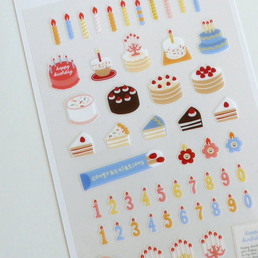 Sheet of decorative Suatelier stickers featuring cakes, candles, and numbers on a white background.